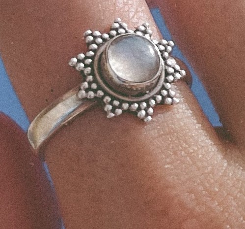 Fotografía de un dedo con acercamiento al anillo de plata con forma de sol 
