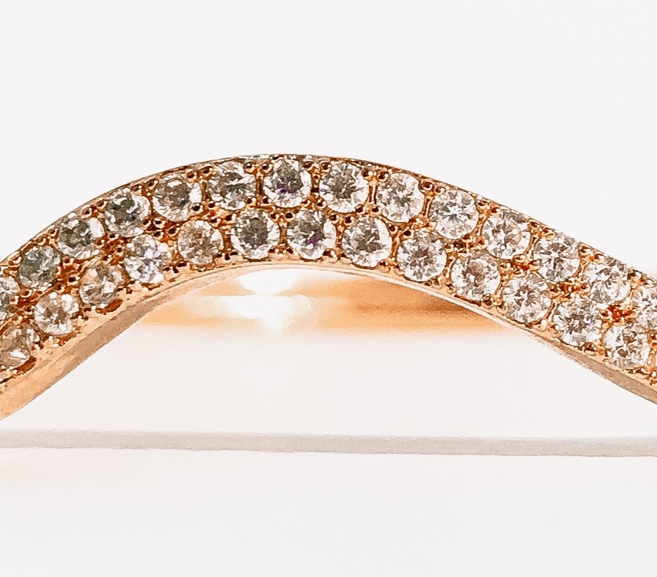 Fotografía de una parte de un brazalete de diamantes incrustados en una linea ondulada de metal dorado